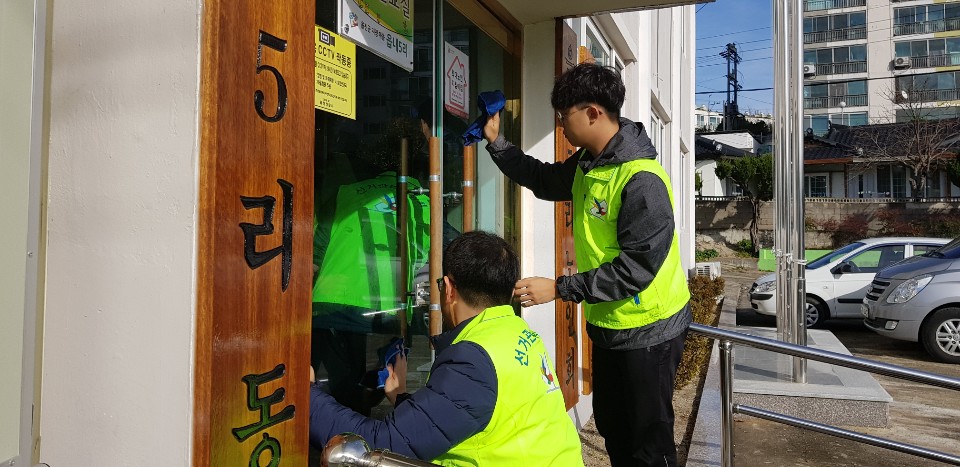울진군선관위 직원과 공정선거지원단이 마을회관 현관문을 닦으며 청소하는 모습입니다.